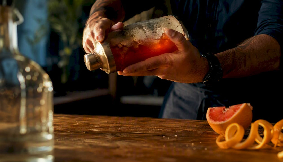 Hands stirring tequila negroni in mixing glass