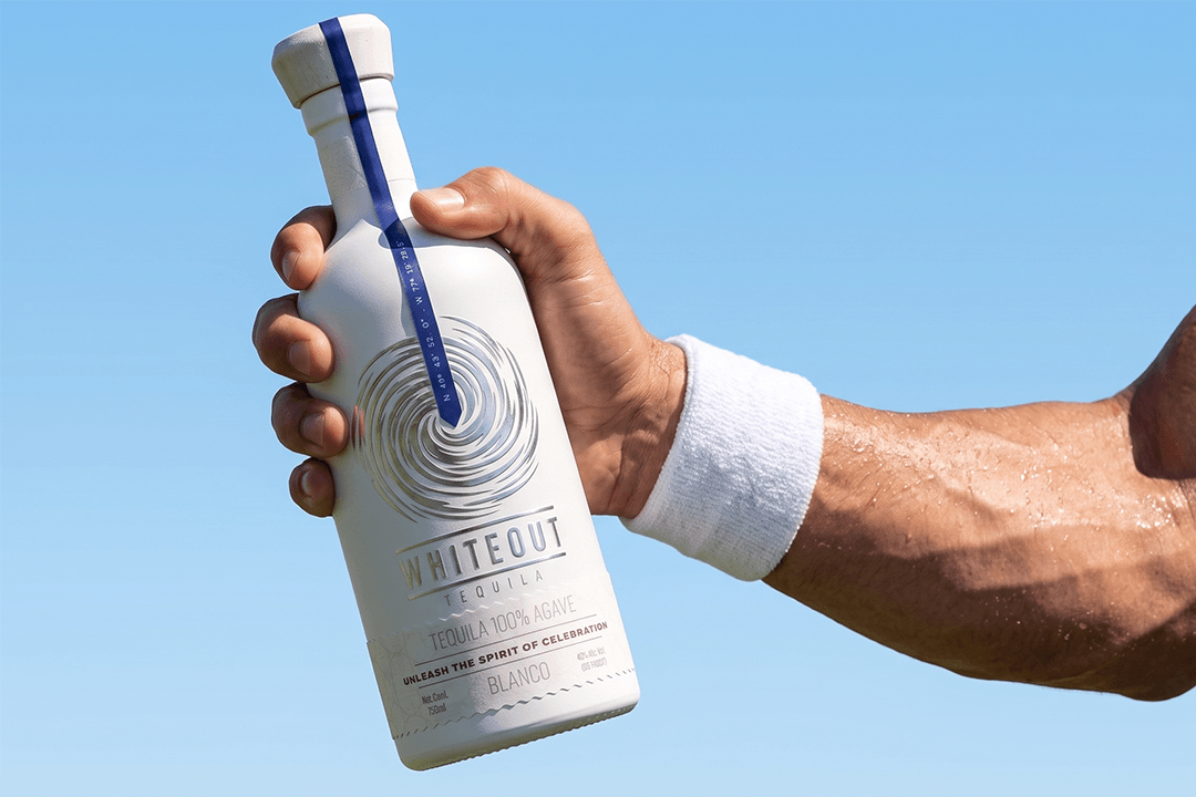 Whiteout Tequila Blanco bottle held outdoors in bright sunlight, showcasing premium 100% agave tequila in an active lifestyle setting.