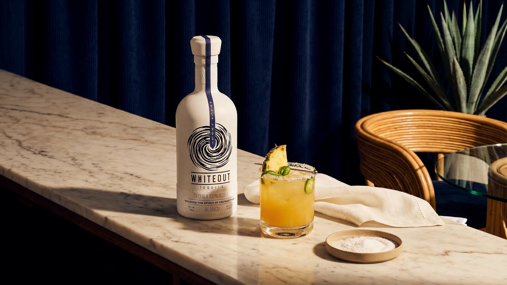 Whiteout tequila bottle next to a pineapple margarita.