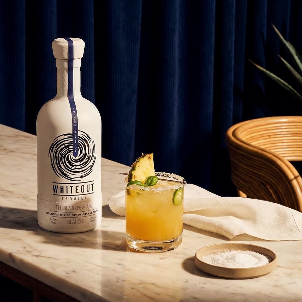 Whiteout tequila bottle next to a pineapple margarita.