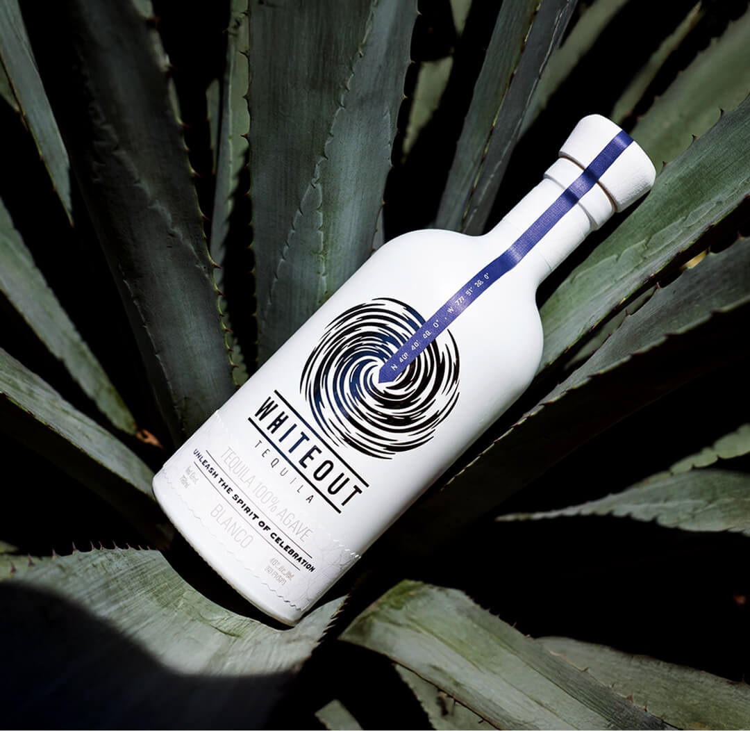 Whiteout Tequila Blanco bottle displayed on agave leaves, highlighting premium 100% agave tequila and Mexican tequila heritage.