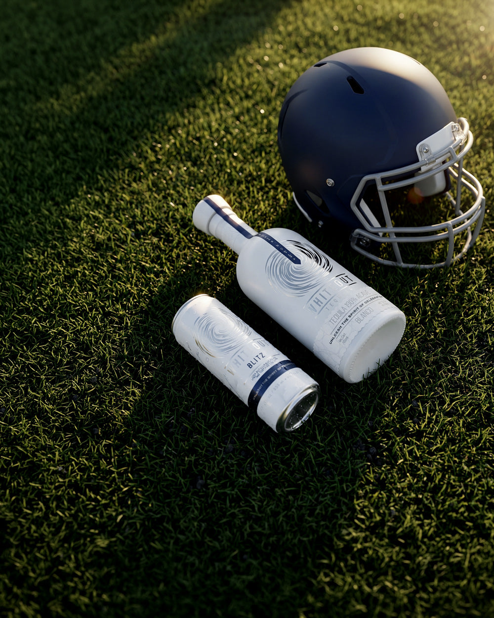 Whiteout tequila products layed on a football field next to a helmet